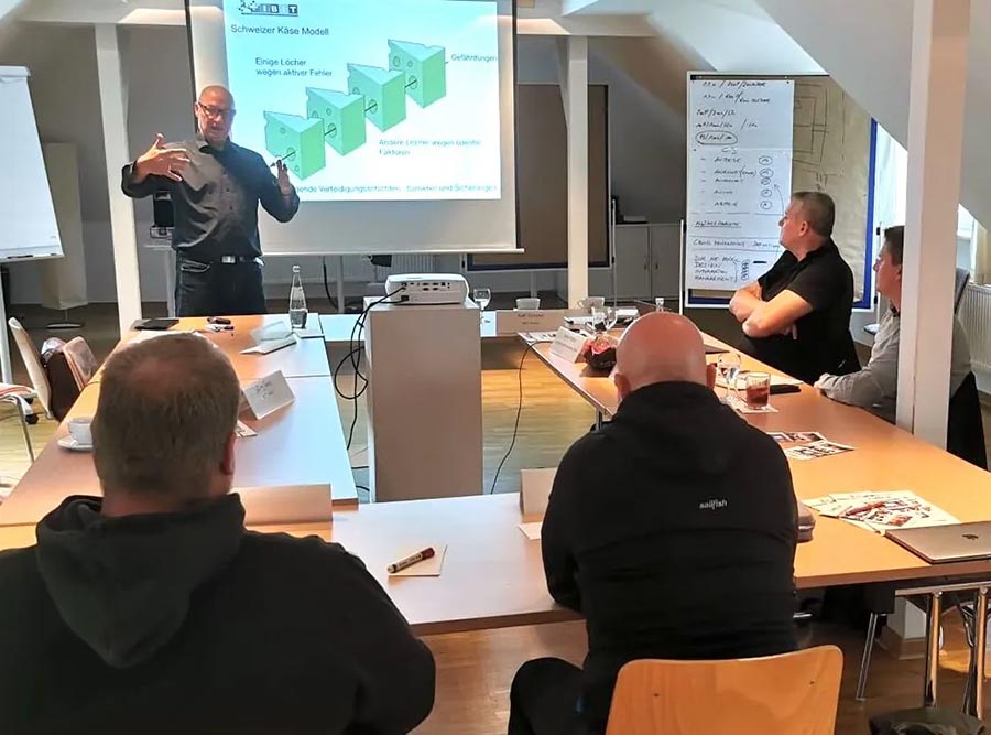 Schulungsszene im IBIT mit einem Referenten, der eine Präsentation hält, während Teilnehmer aufmerksam zuhören.