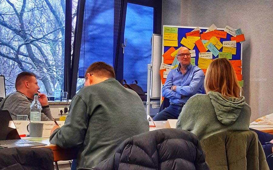 Teilnehmer einer Schulung im IBIT, konzentriert bei der Arbeit, während ein Referent die Inhalte präsentiert.