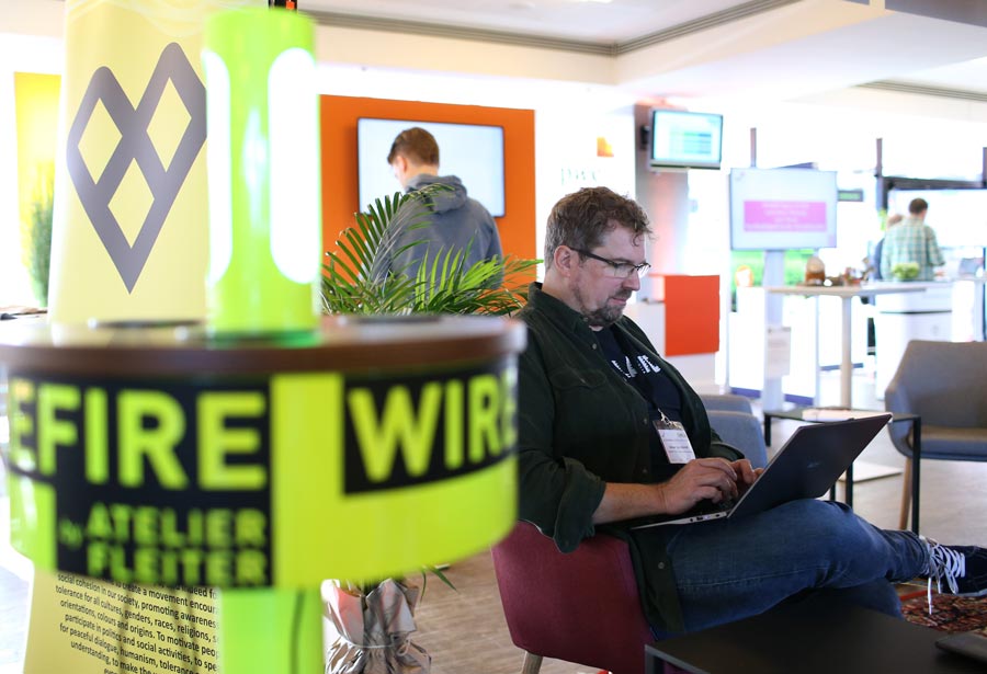 Person arbeitet am Laptop in einem modernen Raum mit Präsentationsmaterialien, passend zur IBIT-Weiterbildung Veranstaltungssicherheit.