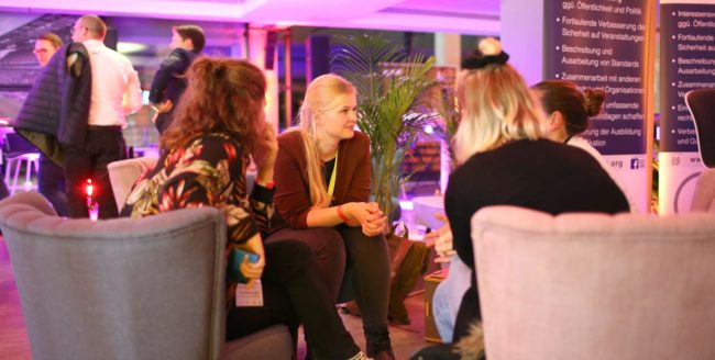 Vier Personen sitzen in einer modernen Lounge-Umgebung und diskutieren angeregt. IBIT-Atmosphäre der Vernetzung.