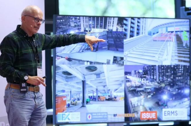 Ein Referent erläutert Sicherheitskonzepte anhand von Bildern auf einem Bildschirm während einer IBIT-Weiterbildung.