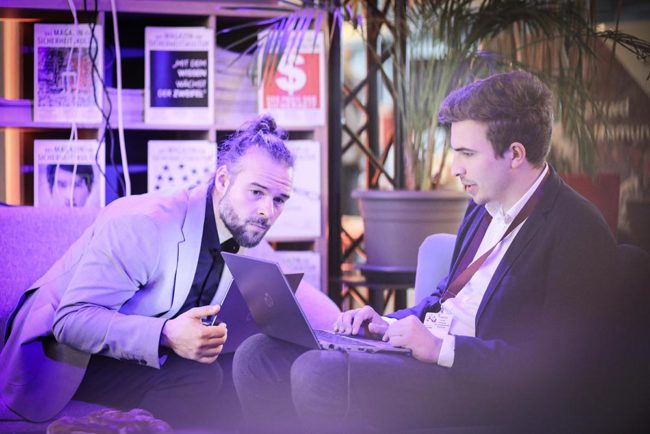 Zwei Personen im Gespräch an einem Laptop, in einer modernen Umgebung mit sanfter Beleuchtung. IBIT.