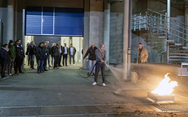 Praktische Schulung zur Brandbekämpfung im Außenbereich, Teilnehmer beobachten einen Einsatz mit Feuerlöscher. IBIT.