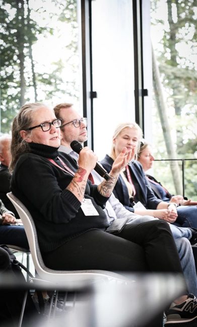 Teilnehmer der IBIT-Fachtagung Veranstaltungssicherheit diskutieren engagiert in einem modernen Raum mit großen Fenstern.