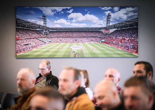 Teilnehmer bei einer IBIT-Veranstaltung, im Hintergrund ein Stadionbild, das die Bedeutung von Sicherheit im Eventbereich symbolisiert.