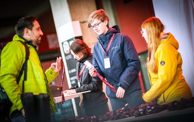 Personen im Gespräch an einem Informationsstand, freundlich und engagiert. IBIT-Weiterbildung zum Thema Veranstaltungssicherheit.