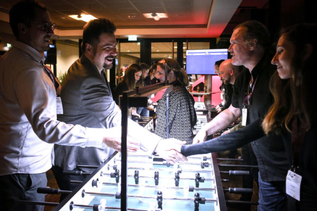 Personen spielen an einem Tischfußballspiel in einer lebhaften Umgebung, ideal für Networking und Austausch beim IBIT.