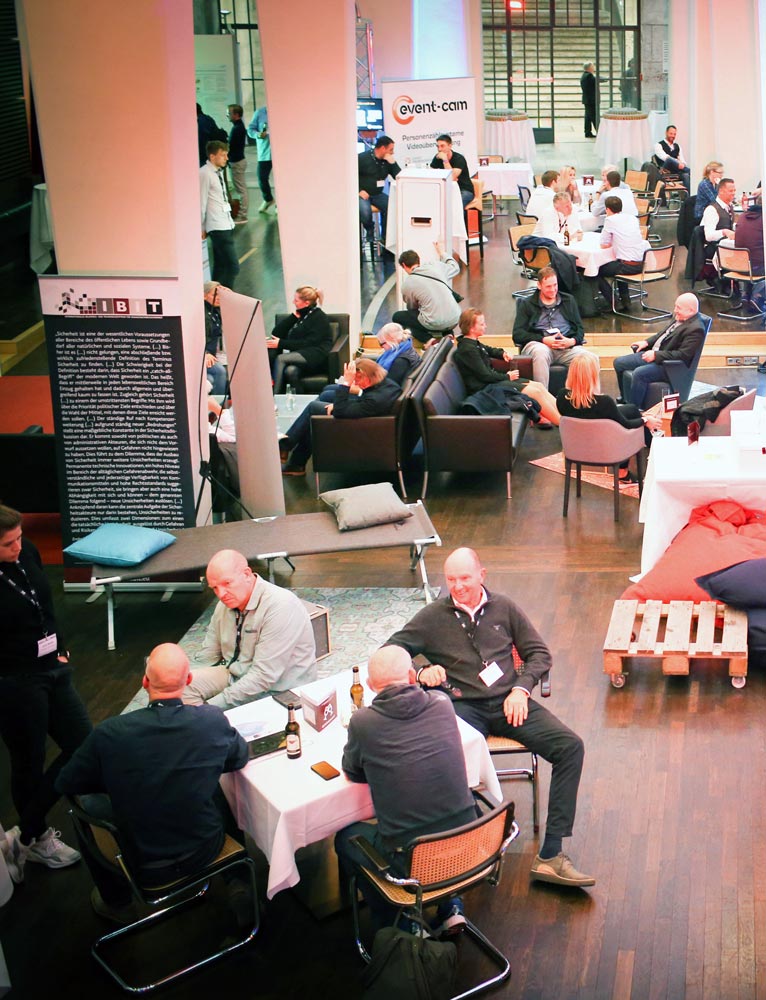 Teilnehmer diskutieren in einer modernen Umgebung während einer IBIT-Veranstaltung zur Veranstaltungssicherheit.