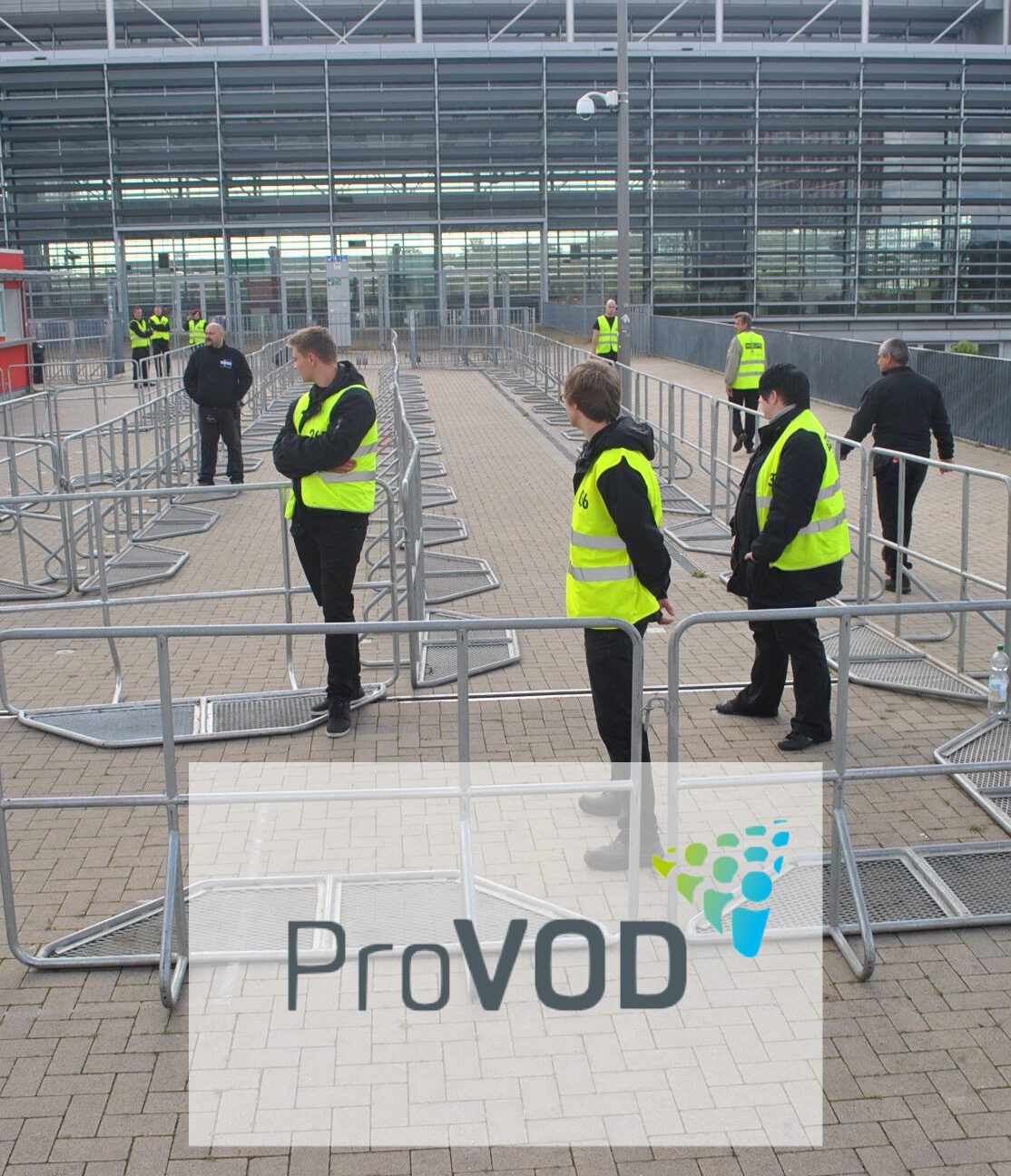 Sicherheitsmitarbeiter in Warnwesten prüfen Absperrungen vor einer Veranstaltung. IBIT-Organisation im Kontext der Veranstaltungssicherheit.