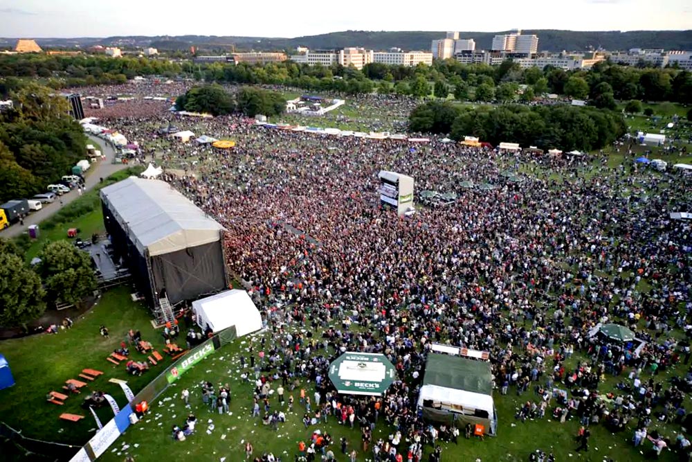 Große Menschenmenge vor einer Bühne im Freien, die Atmosphäre ist lebhaft und festlich. IBIT.