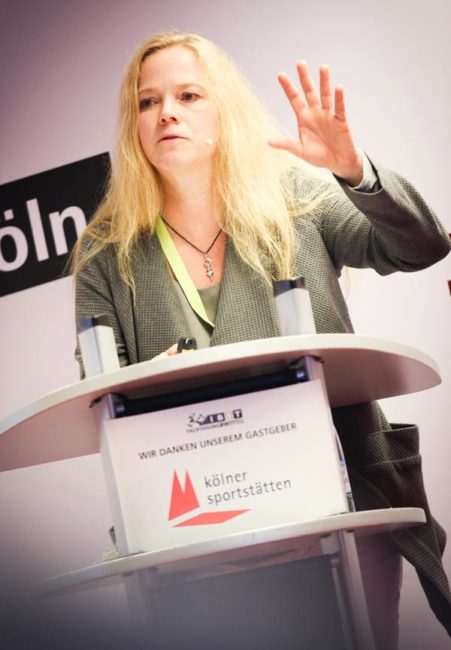 Frau am Rednerpult während einer IBIT-Veranstaltung, die über Veranstaltungssicherheit spricht. Engagierte Stimmung im Raum.