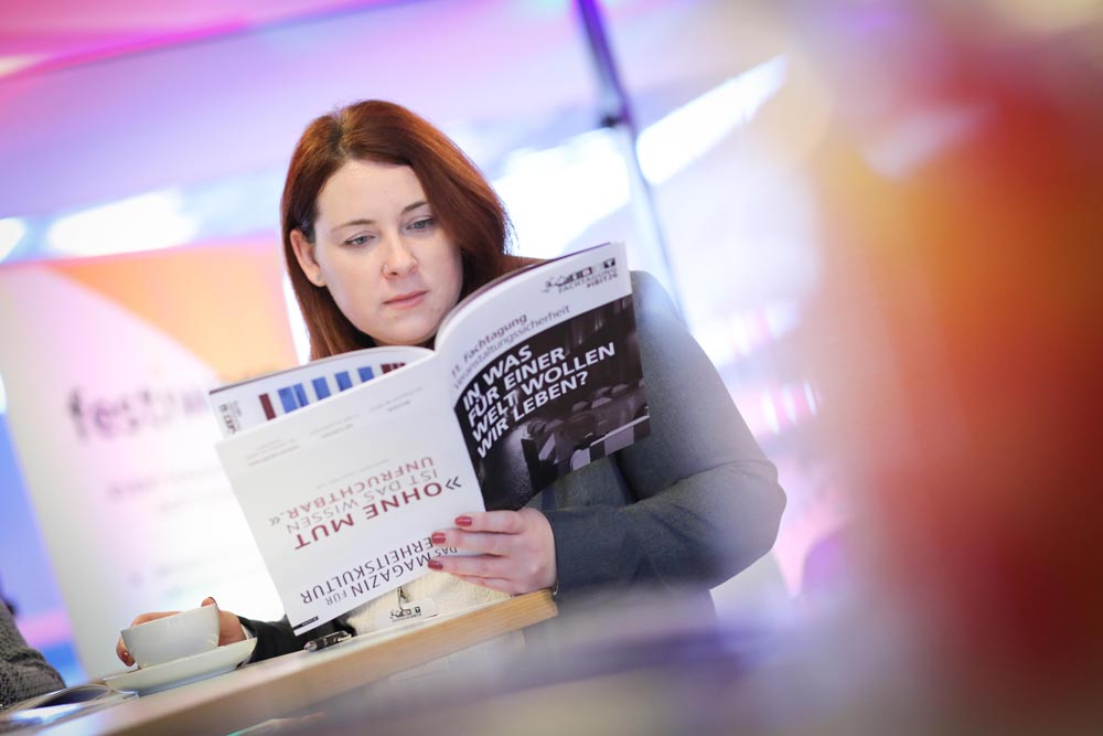 Eine Besucherin der IBIT Fachtagung für Veranstaltungssicherheit liest konzentriert eine Broschüre in einem modernen, hellen Raum. IBIT-Weiterbildung zum Thema Veranstaltungssicherheit.