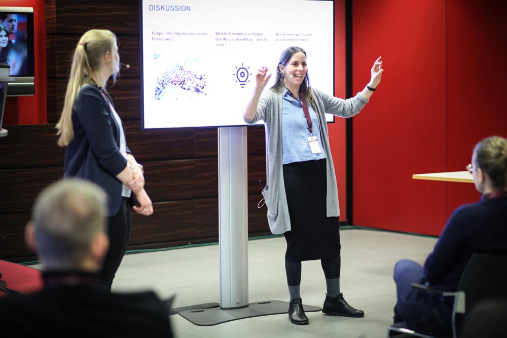 Frau präsentiert während einer IBIT-Weiterbildung zum Thema Veranstaltungssicherheit, Teilnehmer hören aufmerksam zu.